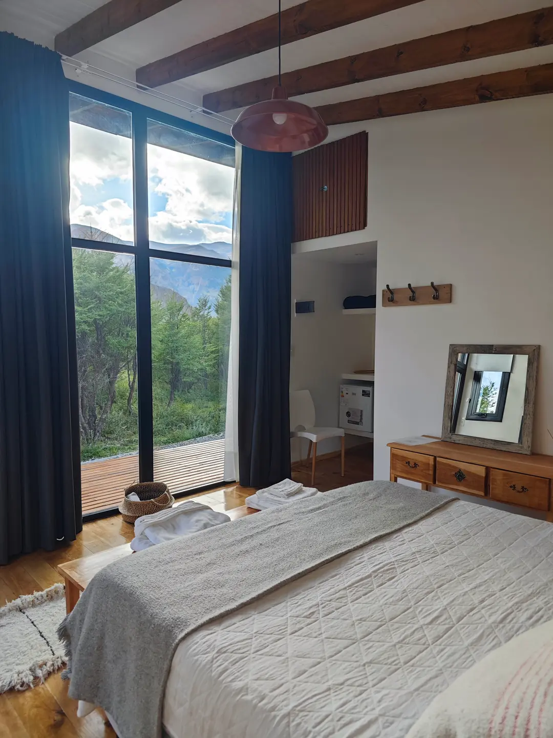 El dormitorio de Puma: la cama, las vigas de madera y el bosque detrás del ventanal.